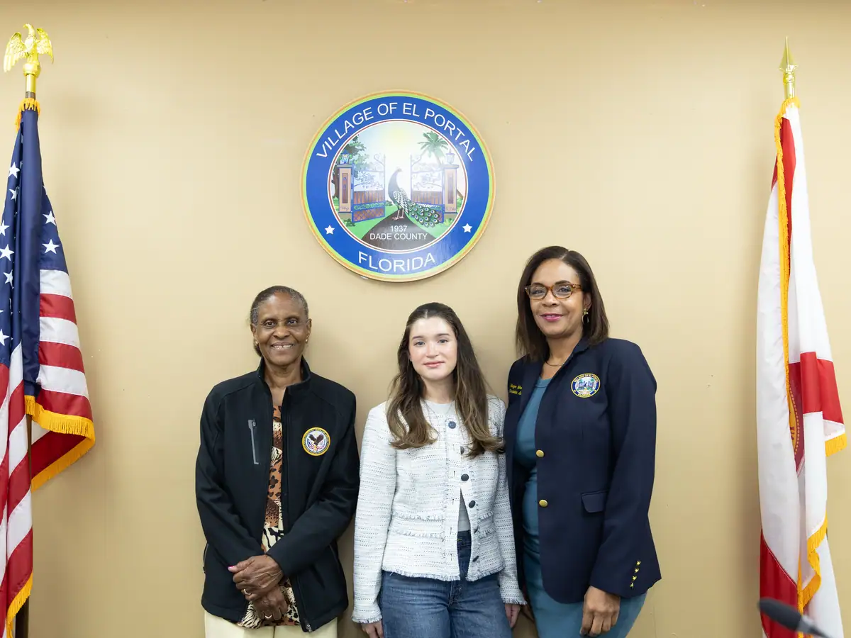 Standing with village leadership beneath the municipal seal.